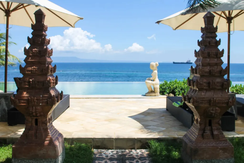 Une piscine à débordement offre une vue sur la mer et le ciel nuageux.