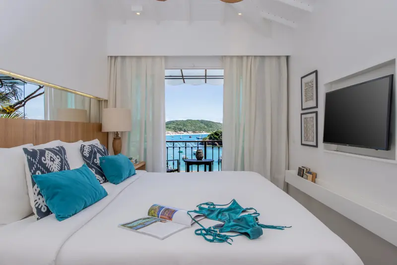 Une chambre lumineuse avec un lit fait face à une vue sur la mer.