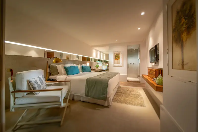 Une chambre lumineuse avec un grand lit et un fauteuil.