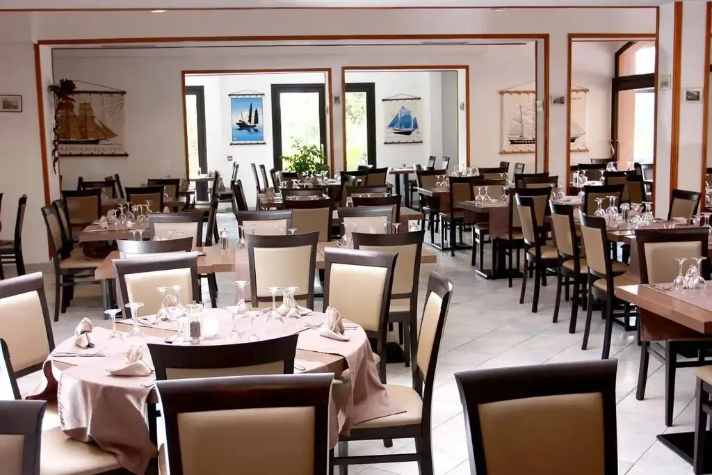 Une salle de restaurant lumineuse avec des tables dressées pour le service.