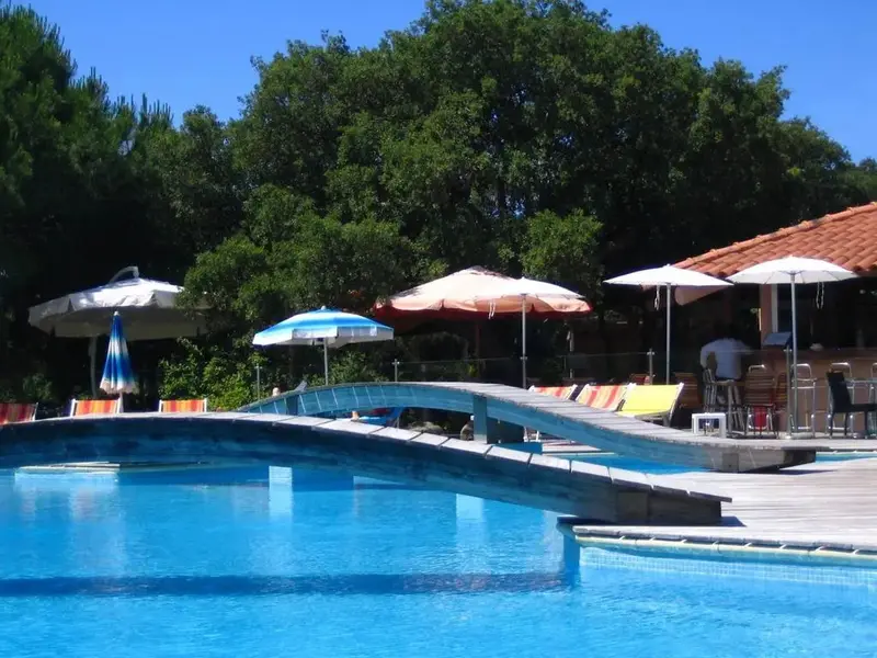 Une piscine avec un ponton en bois et des parasols colorés.