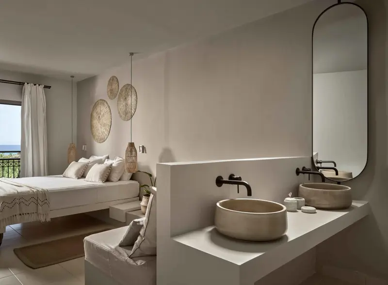 Une chambre lumineuse avec un grand lit et un espace lavabo moderne.