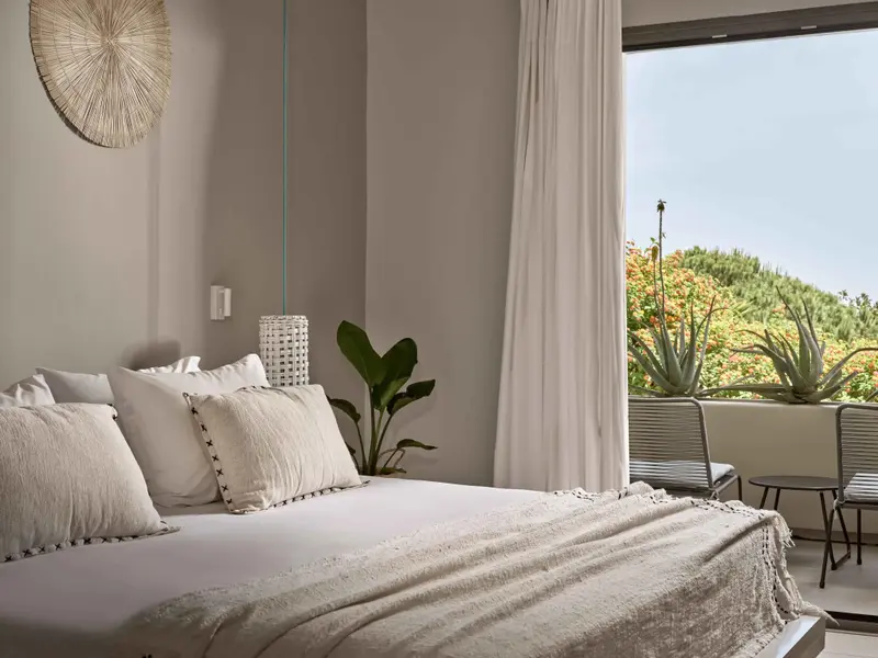 Une chambre lumineuse avec un grand lit et une vue sur la végétation.