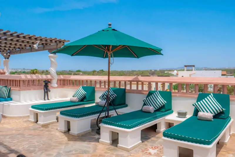 Terrasse aménagée avec des chaises longues et un parasol vert offrant une vue sur le paysage.