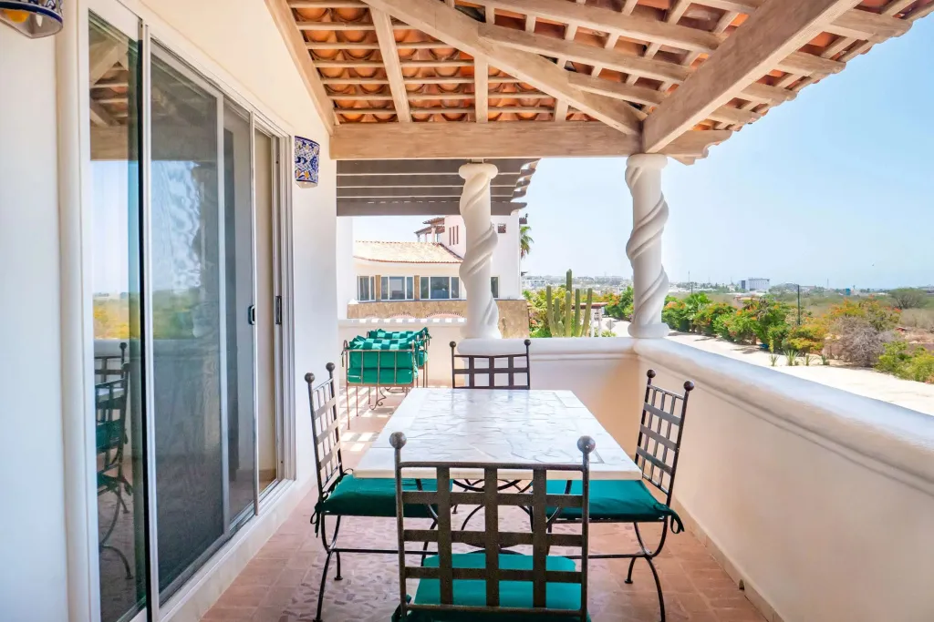 Une terrasse ombragée avec une table et des chaises offre une vue sur le paysage.