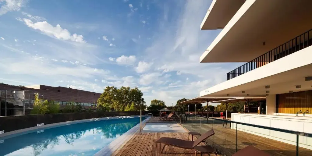 Une piscine rectangulaire bordée d'une terrasse en bois avec des chaises longues.