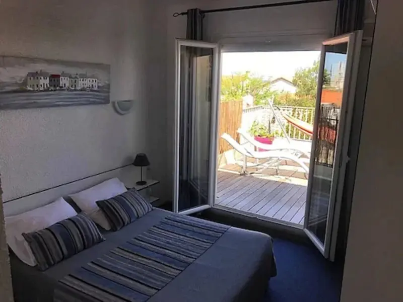 Une chambre lumineuse s'ouvre sur une terrasse avec des transats.