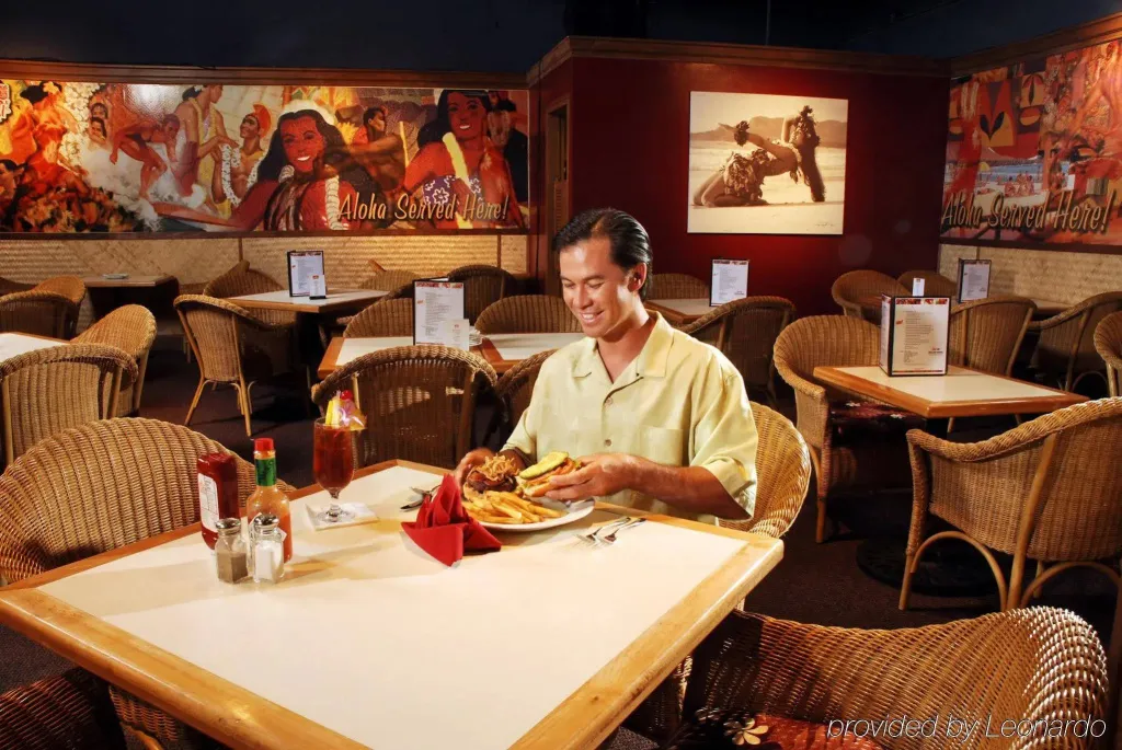 Un homme souriant déguste un repas à une table dans une salle lumineuse.