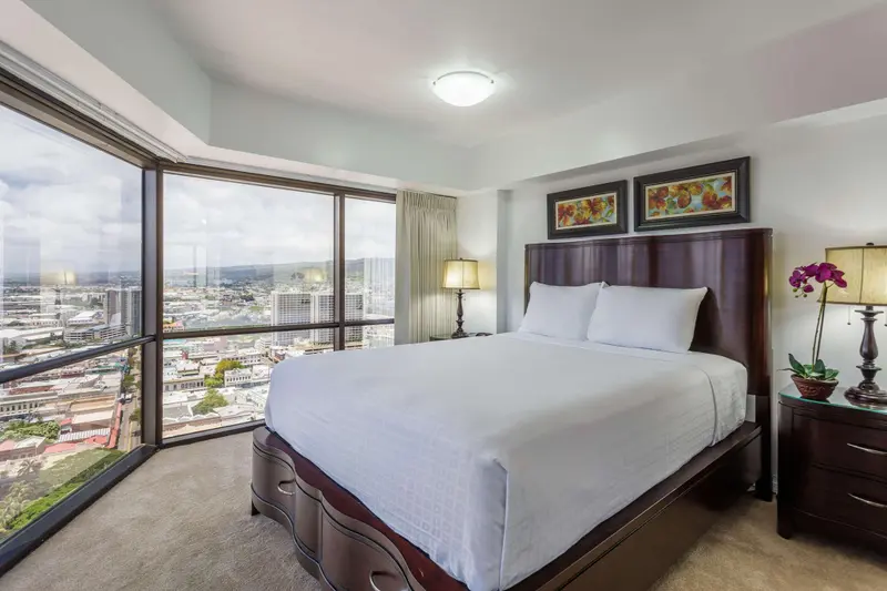 Une chambre lumineuse avec un grand lit et une vue sur la ville.