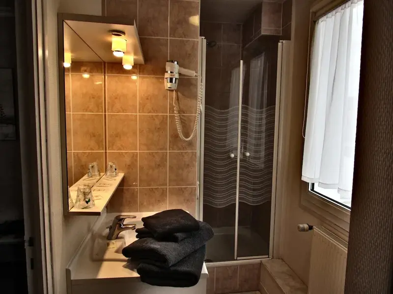 Une salle de bain avec douche vitrée et lavabo.