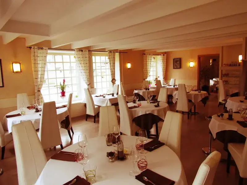 Une salle lumineuse avec des tables dressées pour un repas.