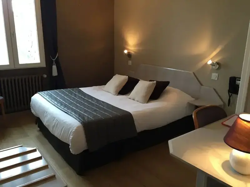 Une chambre lumineuse avec un grand lit recouvert d'une couette et de coussins.