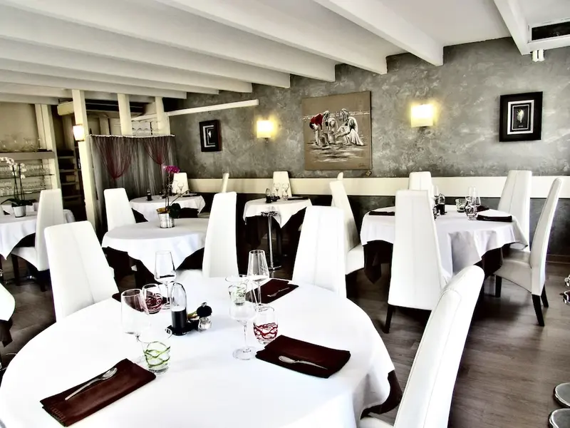 Une salle de restaurant lumineuse avec des tables nappées et des chaises blanches.