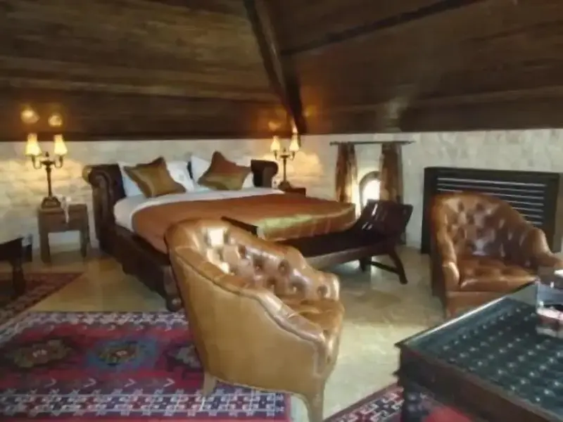 Une chambre à coucher spacieuse avec un grand lit et des fauteuils confortables.