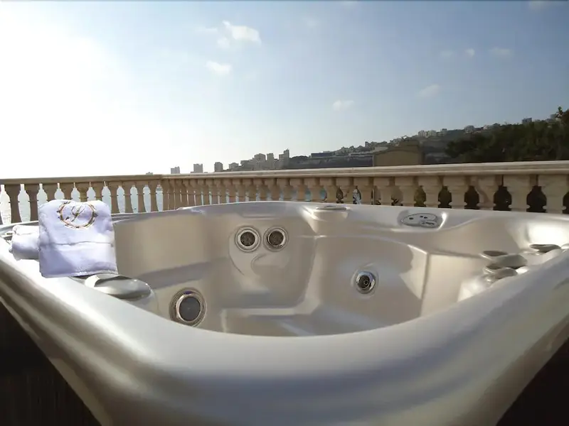 Un jacuzzi rempli d'eau avec des serviettes posées sur le bord, vu d'un balcon avec une rambarde.