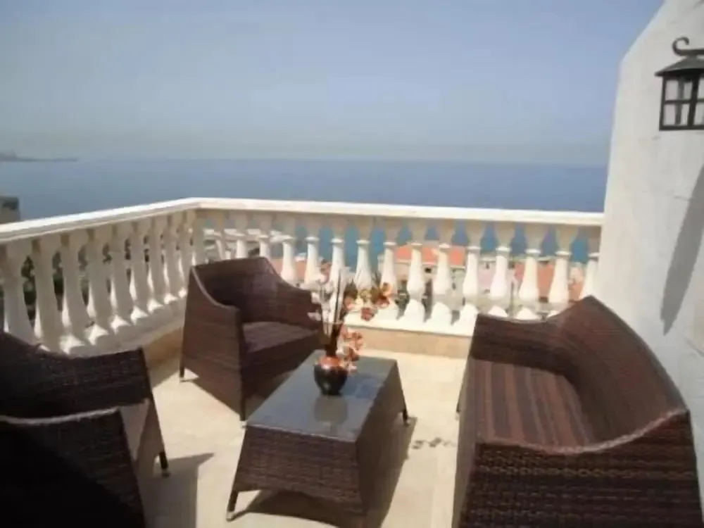 Terrasse aménagée avec mobilier en rotin donnant sur la mer.