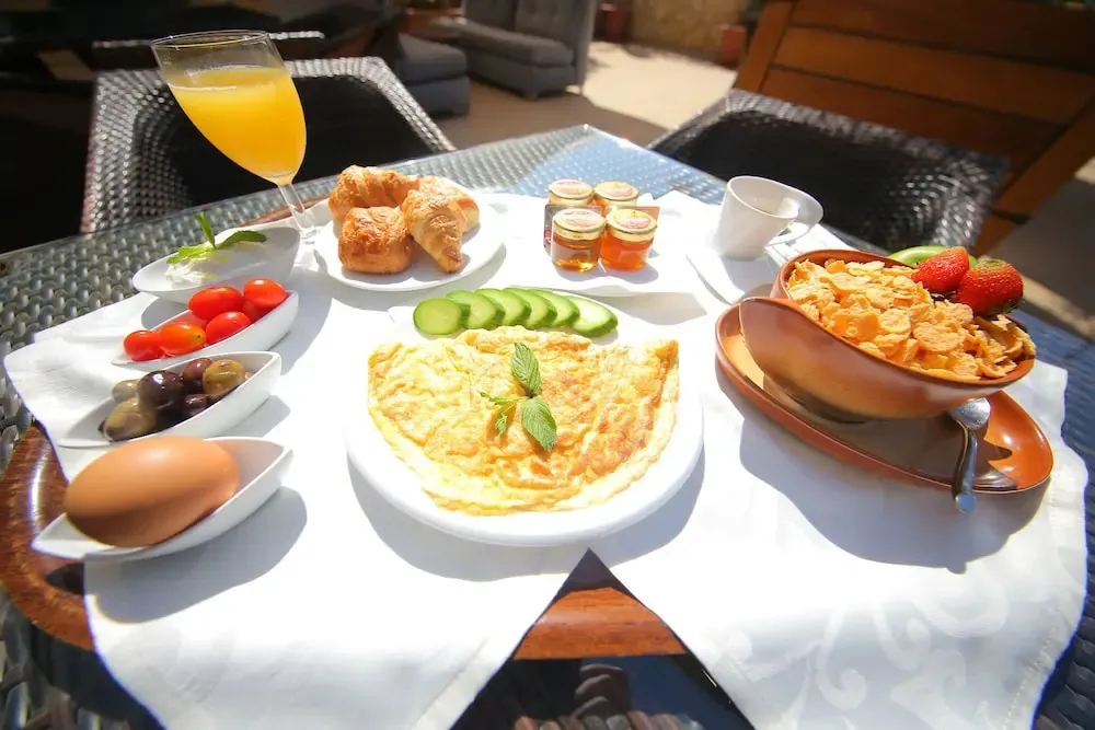Un petit-déjeuner copieux est présenté sur une table ensoleillée.