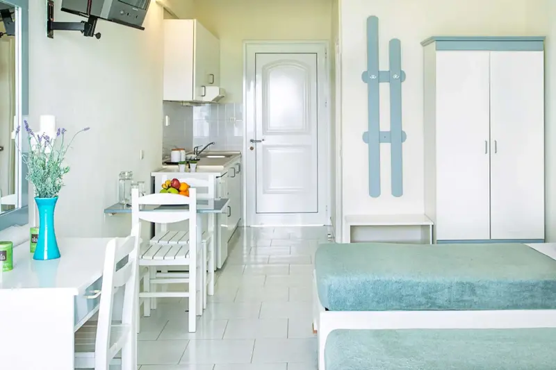 Une kitchenette lumineuse s'ouvre sur un espace de vie avec un lit.