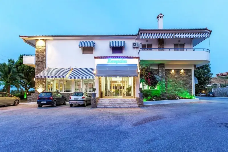 Façade d'un bâtiment blanc avec des voitures garées devant et des stores rayés.