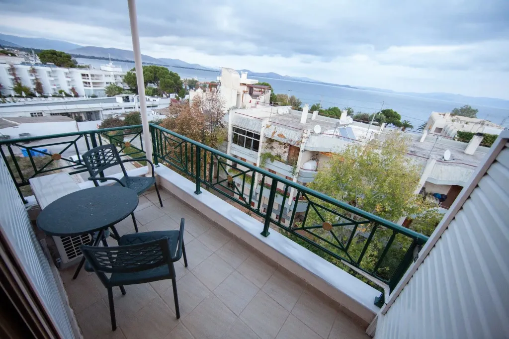 Une terrasse avec mobilier de jardin offre une vue sur la mer et les bâtiments environnants.
