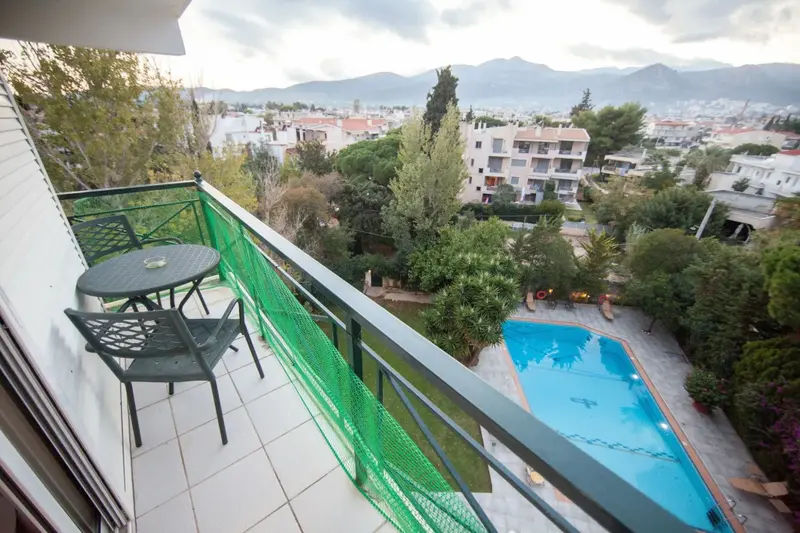Une terrasse avec une table et des chaises offre une vue sur une piscine et un paysage montagneux.