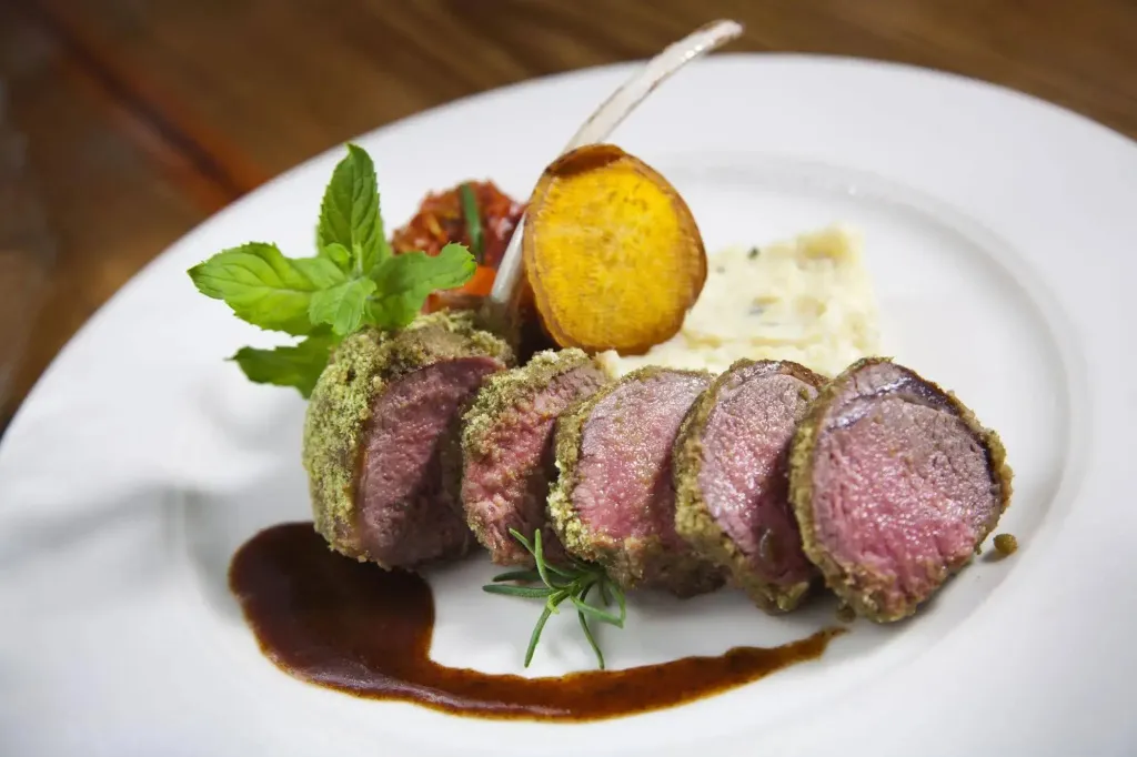 Assiette de viande rouge panée accompagnée de légumes et de sauces.