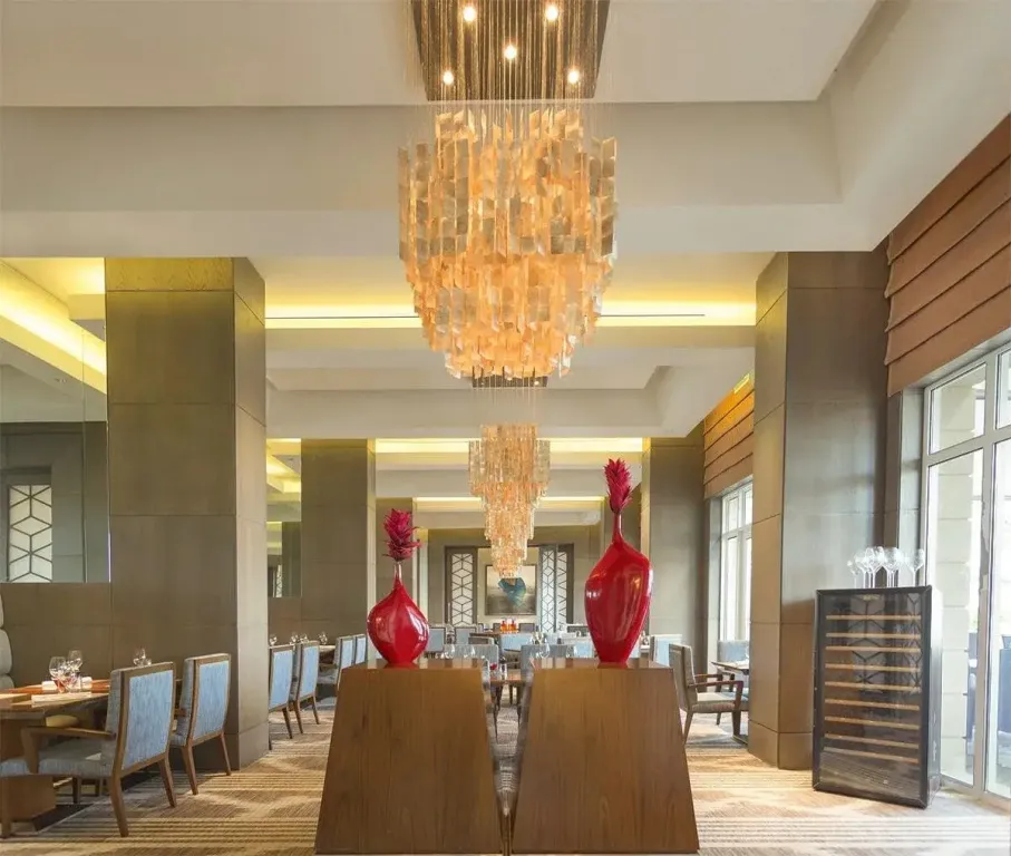 Une salle lumineuse avec des tables dressées et un grand lustre décoratif.