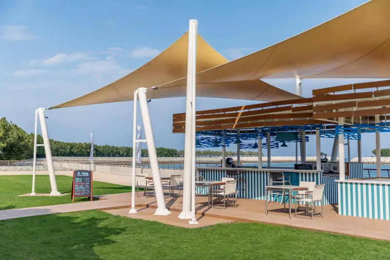 Un espace extérieur ombragé avec un bar et des tables.