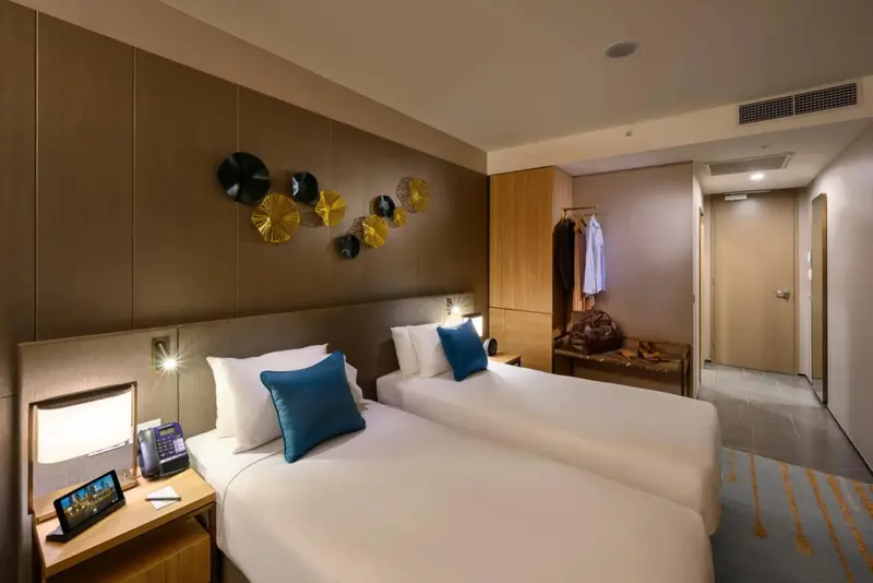 Deux lits simples avec oreillers bleus dans une chambre lumineuse.