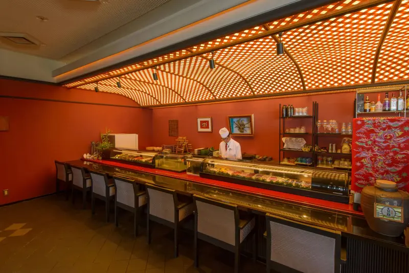 Un comptoir de restaurant japonais avec un chef préparant des sushis.