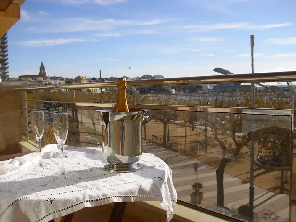 Une table avec des verres et une bouteille de champagne sur un balcon avec vue sur la ville.