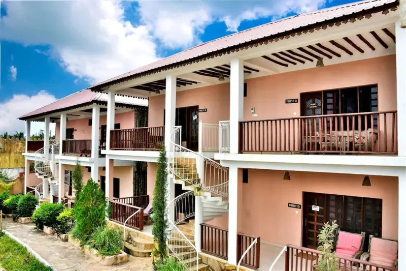 Bâtiment à deux étages avec des balcons et une végétation luxuriante.