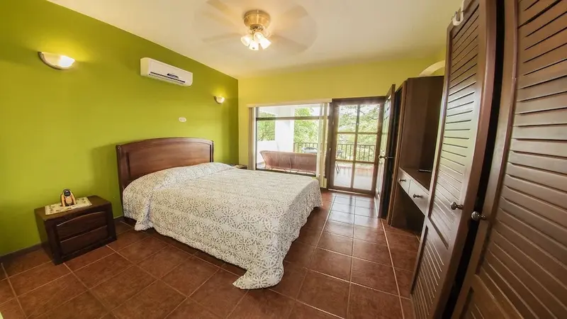 Une chambre lumineuse avec un grand lit et un accès à un balcon.