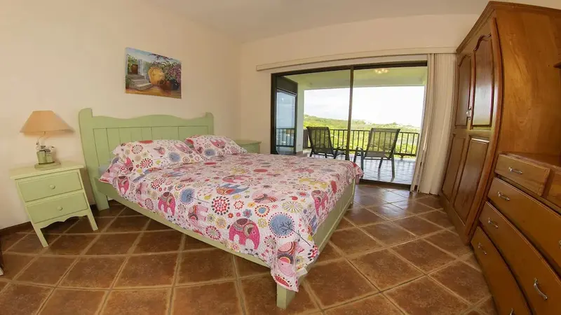 Une chambre lumineuse s'ouvre sur une terrasse avec vue sur la végétation.