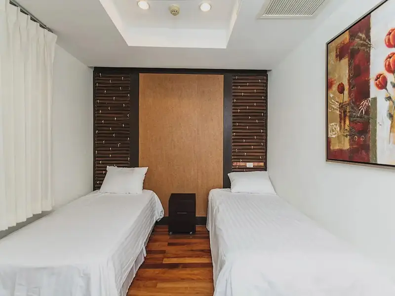 Une chambre lumineuse avec deux lits simples et une décoration murale.