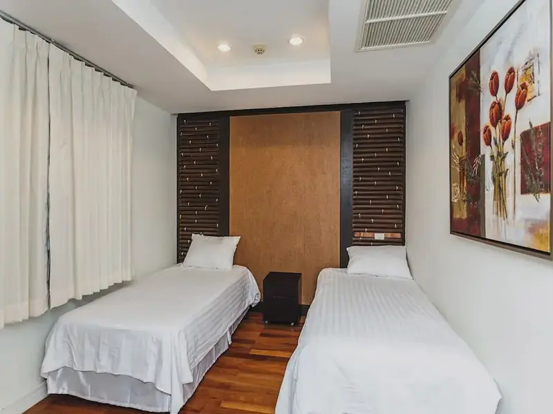 Une chambre lumineuse avec deux lits simples et une décoration murale.