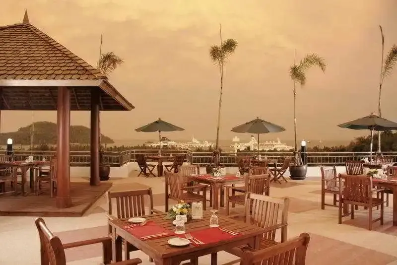Une terrasse de restaurant avec des tables dressées et une vue sur la mer au loin.