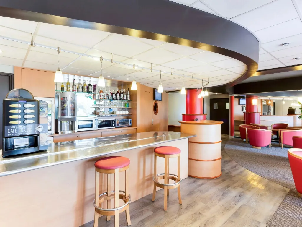 Un comptoir de bar moderne avec des tabourets et une sélection de boissons.