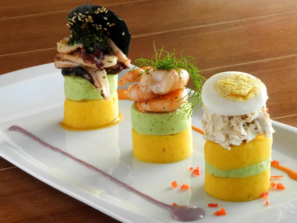 Trois présentations culinaires colorées sont disposées sur une assiette blanche.