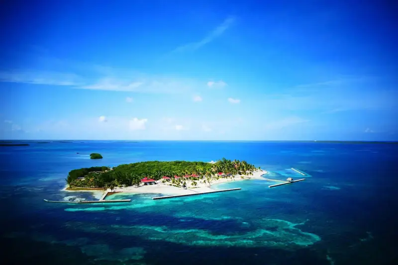 Vue aérienne d'une île tropicale bordée de plages et de végétation luxuriante.