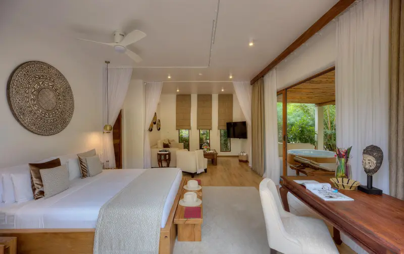 Une chambre lumineuse s'ouvre sur une salle de bain avec baignoire extérieure.