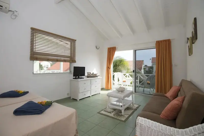 Espace de vie lumineux avec canapé et accès à un balcon.