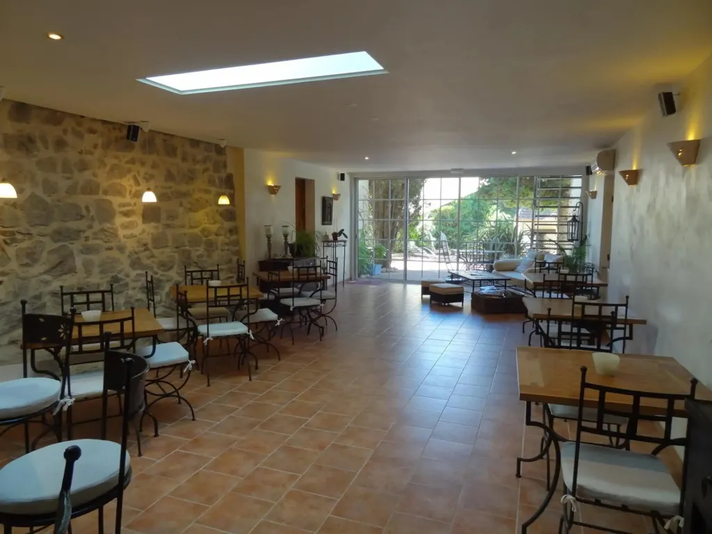 Une salle lumineuse avec des tables et des chaises disposées sur un sol carrelé.