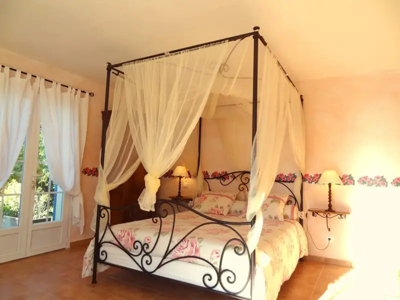 Une chambre à coucher lumineuse avec un lit à baldaquin décoré de voilages.
