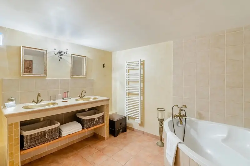 Une salle de bain lumineuse avec deux vasques et une baignoire.