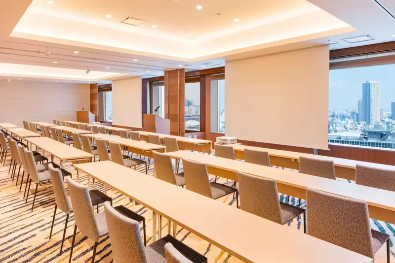 Une salle de réunion lumineuse avec des tables alignées face à un écran.