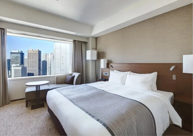 Une chambre lumineuse avec un grand lit et une vue sur la ville.