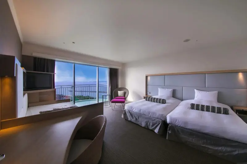 Une chambre lumineuse avec deux lits simples et une vue sur la mer.