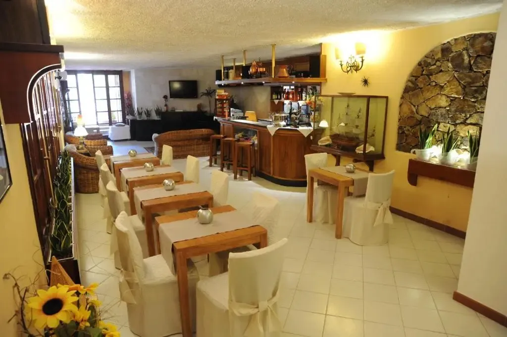 Une salle lumineuse avec des tables et des chaises, un comptoir de bar et un coin salon.