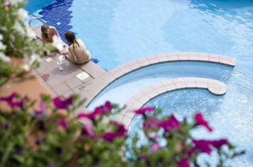 Deux femmes discutent au bord d'une piscine ensoleillée.